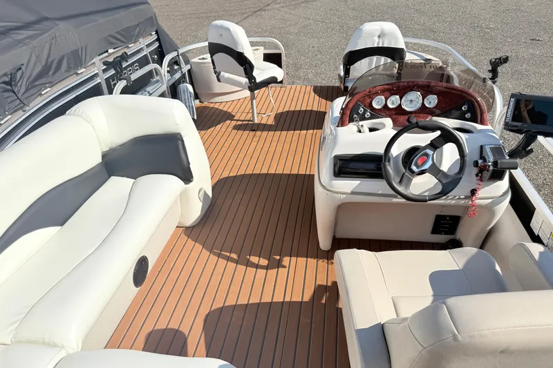Slide: The Image of 2011 Sun Tracker Fishin' Barge 21 interior with seating, steering console, and wood-style flooring. - 16