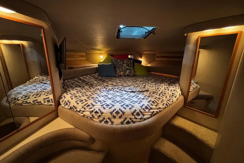 Slide: The Image of Cozy cabin interior of 1994 Sea Ray 400 Express Cruiser with patterned bedding and mirrors. - 8