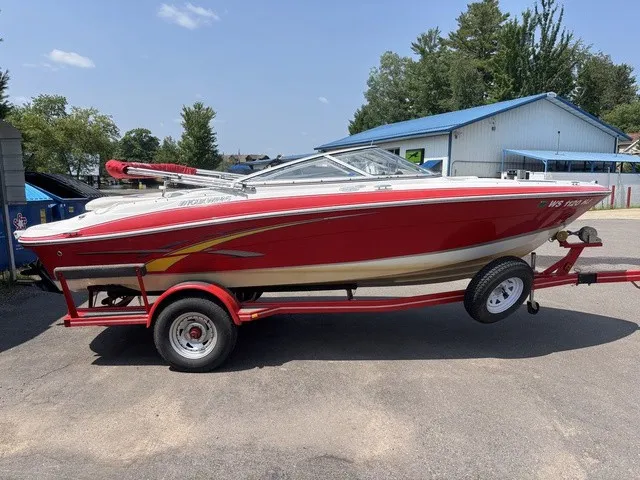 The Image of A red 2007 Four Winns 200 Horizon boat on a trailer, parked in a lot. - 1