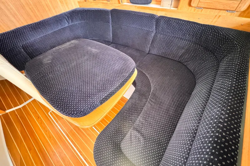 Slide: The Image of Interior of a 2006 Catalina 34 MkII sailboat with plush navy seating and wooden flooring. - 8