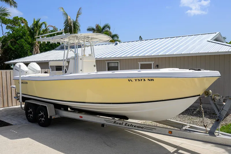 Slide: The Image of 2007 Competition 25 boat on trailer, yellow hull, parked near a house with palm trees. - 5