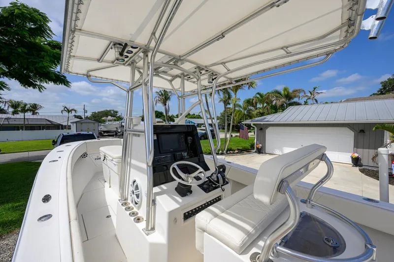 Slide: The Image of 2007 Competition 25 boat interior with steering console and seating, parked in a driveway. - 20
