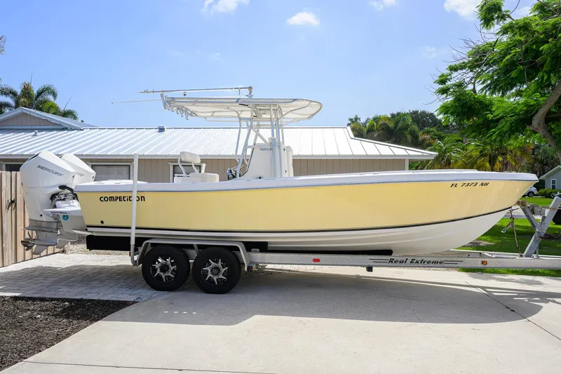 The Image of 2007 Competition 25 boat on trailer, yellow hull, parked in driveway. - 0