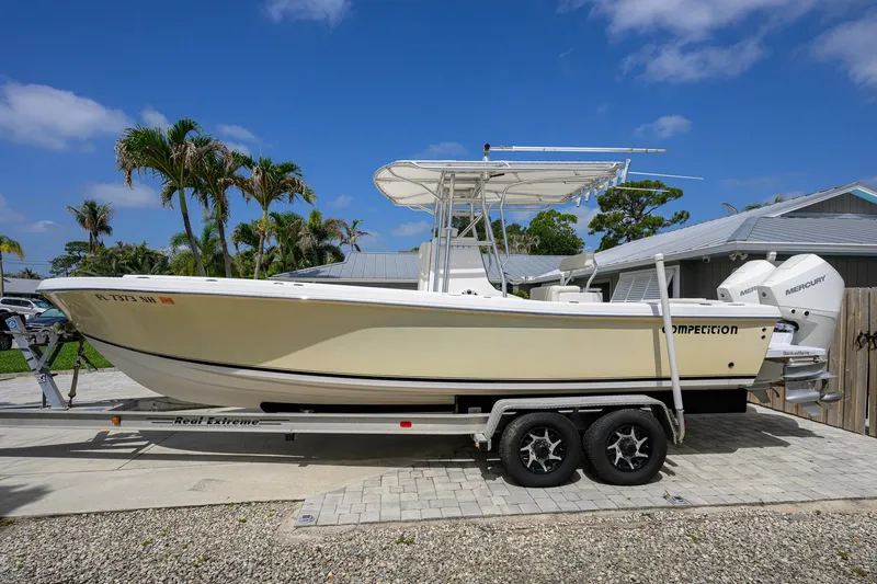 Slide: The Image of 2007 Competition 25 boat on trailer, parked outdoors with palm trees and blue sky. - 12