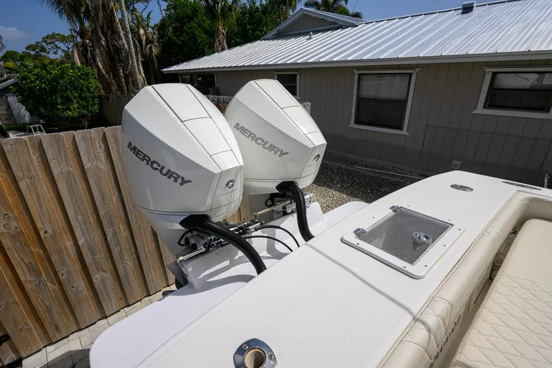 Slide: The Image of Twin Mercury outboard engines on a 2007 Competition 25 boat, parked near a wooden fence. - 31