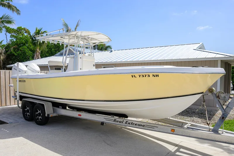 Slide: The Image of 2007 Competition 25 boat on trailer, yellow hull, parked near a house with palm trees. - 6