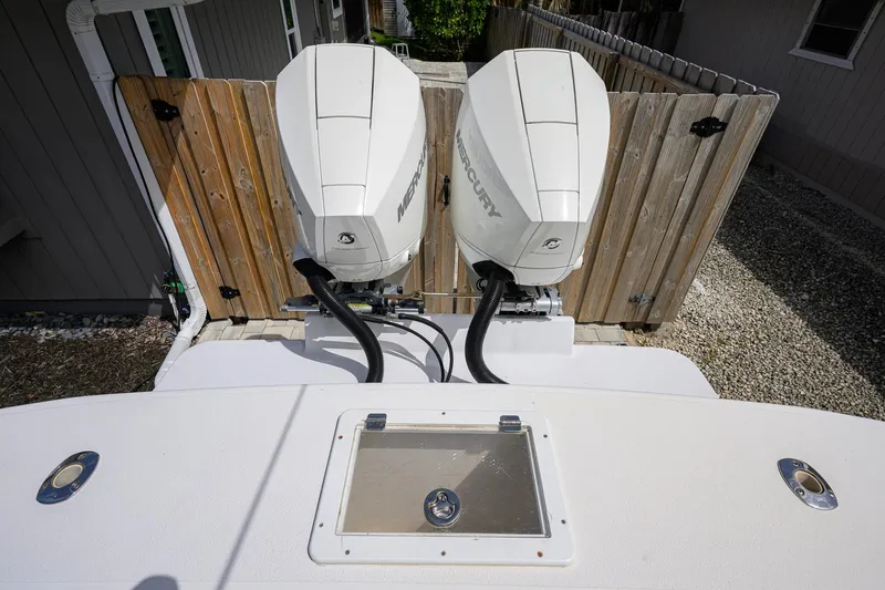 Slide: The Image of Twin Mercury outboard engines on a 2007 Competition 25 boat, docked near a wooden fence. - 30