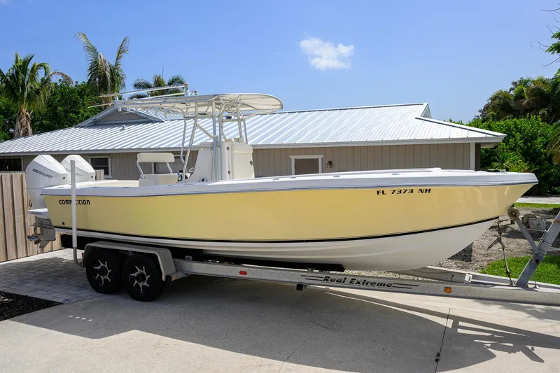 Slide: The Image of 2007 Competition 25 boat on trailer, parked near a house with palm trees. - 7