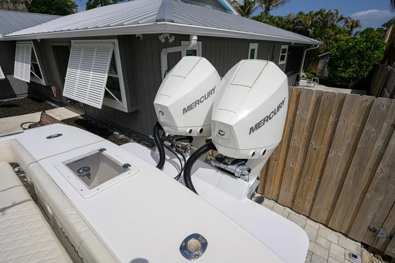 Slide: The Image of Twin Mercury outboard engines on a 2007 Competition 25 boat, near a house with open shutters. - 32