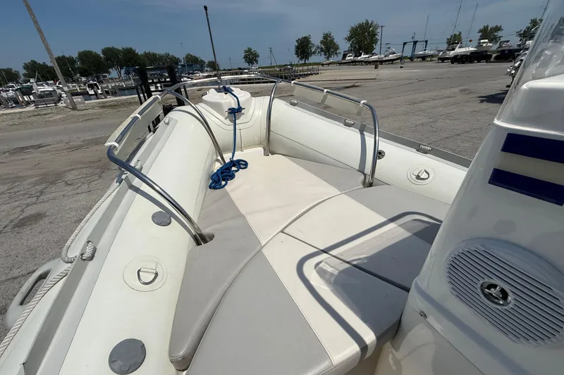 Slide: The Image of 2014 Marlago 520CC boat interior with cushioned seating and railing at a marina. - 9