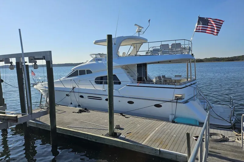 The Image of Luxury 2003 Johnson FLY yacht docked, featuring spacious deck and American flag. - 1