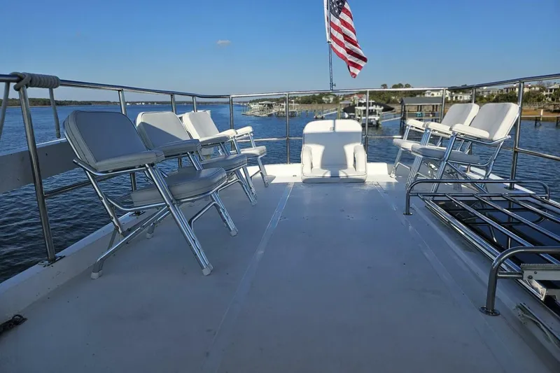 Slide: The Image of Deck of 2003 Johnson FLY boat with chairs and American flag, overlooking water. - 12
