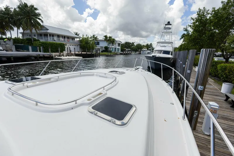 Slide: The Image of 2000 Tiara Yachts 5200 Express docked near waterfront homes, under a partly cloudy sky. - 27