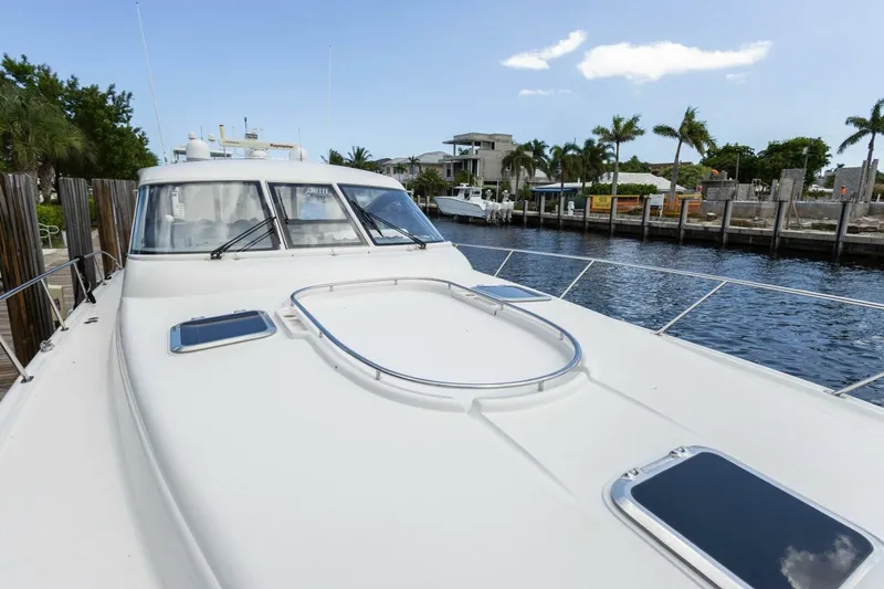 Slide: The Image of 2000 Tiara Yachts 5200 Express docked by waterfront homes, clear sky. - 25