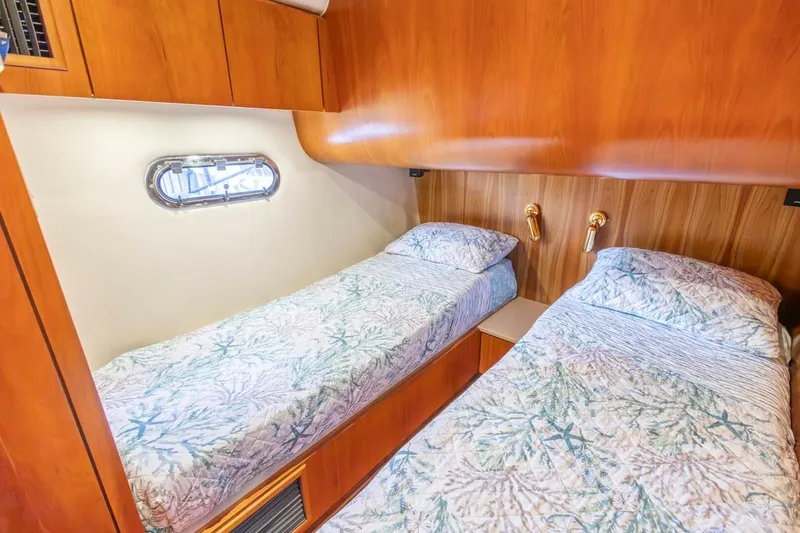 Slide: The Image of Twin beds in a 2000 Tiara Yachts 5200 Express cabin with wood paneling and porthole. - 18