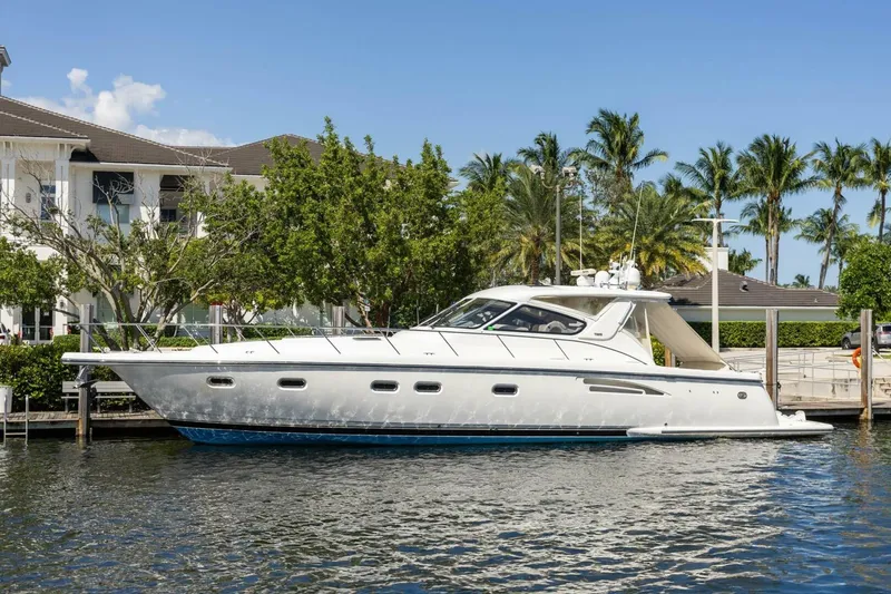 Slide: The Image of 2000 Tiara Yachts 5200 Express docked by palm trees and waterfront homes. - 1