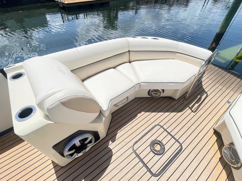 Slide: The Image of A sleek pontoon boat with cream-colored seating and wooden flooring, docked by the water. - 42
