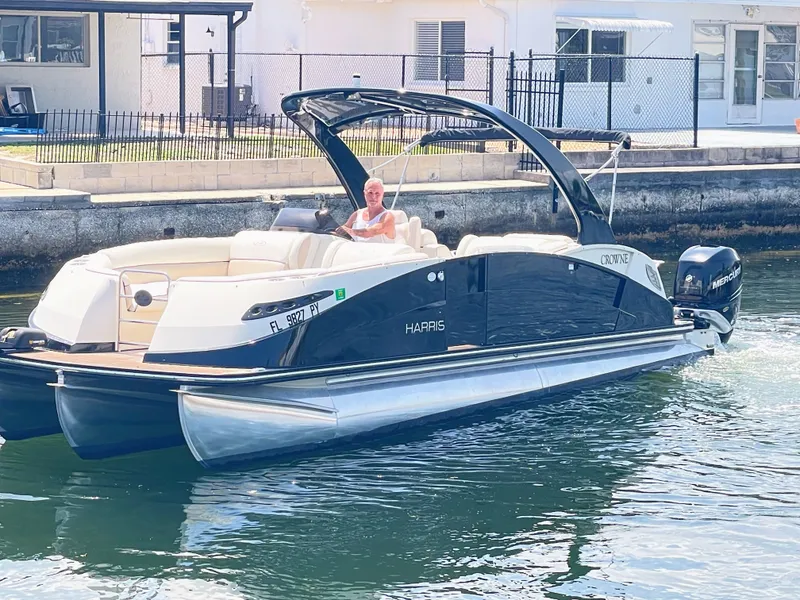 Slide: The Image of A 2015 Harris FloteBote Crown DL 250 on the water. A man is seated at the helm. - 12