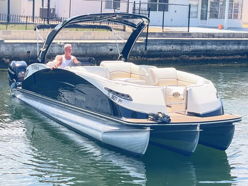 Slide: The Image of A 2015 Harris FloteBote Crown DL 250 on the water. It features a sleek design with beige seating. - 14
