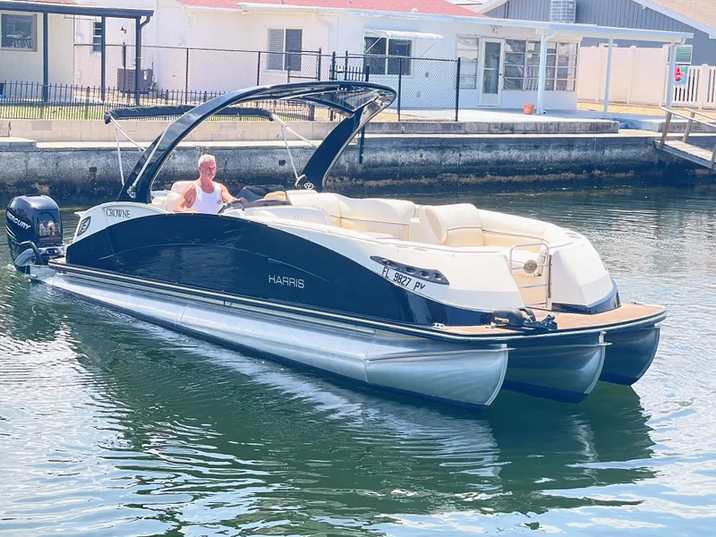 Slide: The Image of A 2015 Harris FloteBote Crown DL 250 on calm water. A man is steering the boat. - 15