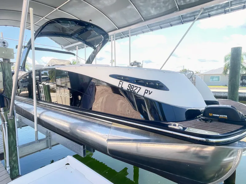 Slide: The Image of A sleek pontoon boat with a glossy black hull, docked under a covered area. - 2