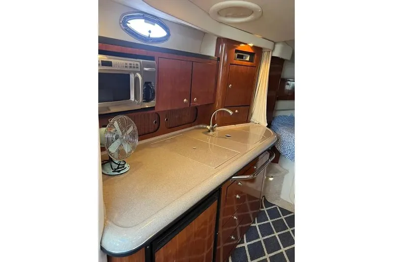 Slide: The Image of 2006 Sea Ray 340 Sundancer interior kitchen with microwave, sink, and wooden cabinetry. - 6