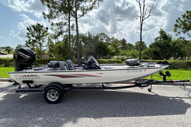 The Image of 2020 Triton 18 TX boat on trailer, parked outdoors with trees in the background. - 0