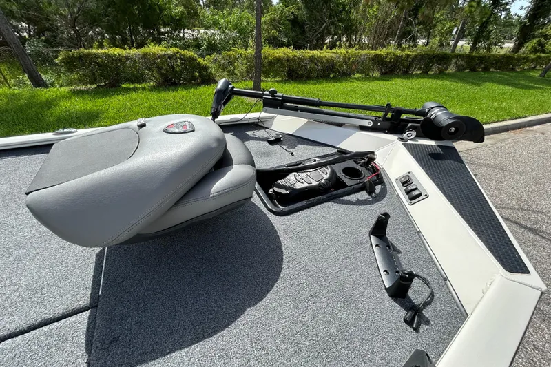 Slide: The Image of 2020 Triton 18 TX boat deck with seating and trolling motor, surrounded by greenery. - 15