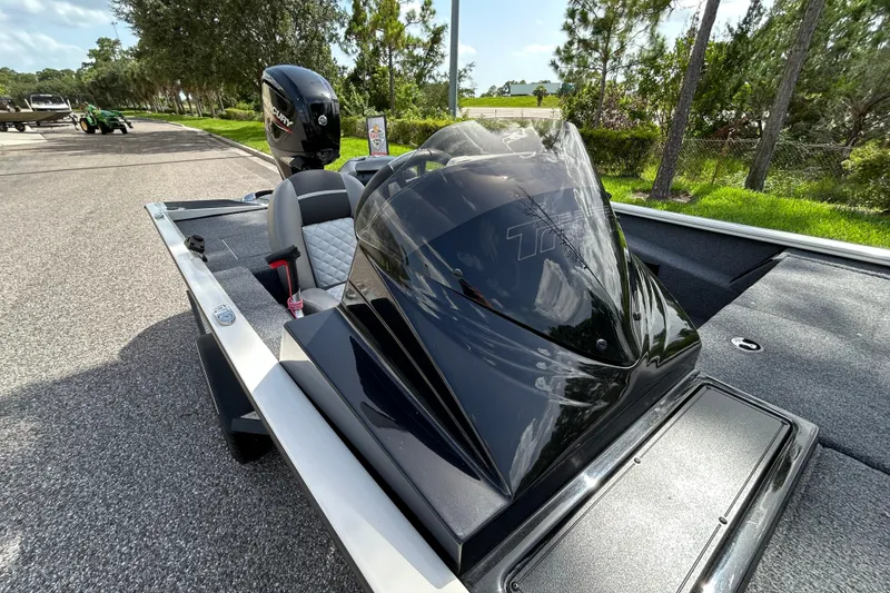 Slide: The Image of 2020 Triton 18 TX boat with sleek black console and Mercury engine, parked on a sunny day. - 13