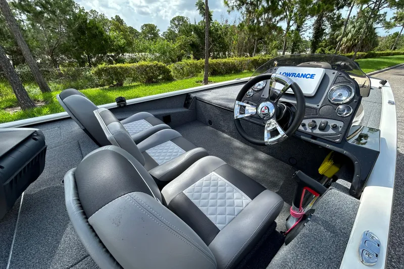 Slide: The Image of 2020 Triton 18 TX boat interior with steering wheel and dual seats, surrounded by lush greenery. - 9