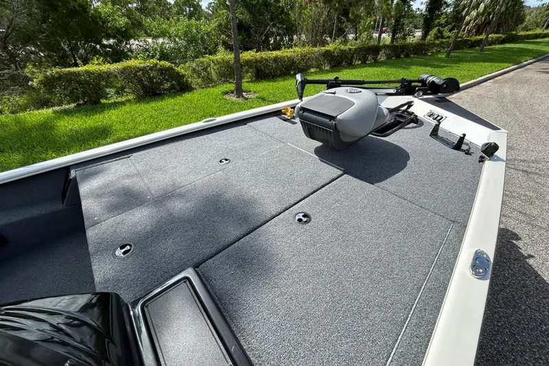 Slide: The Image of 2020 Triton 18 TX boat deck with trolling motor, surrounded by lush greenery. - 14