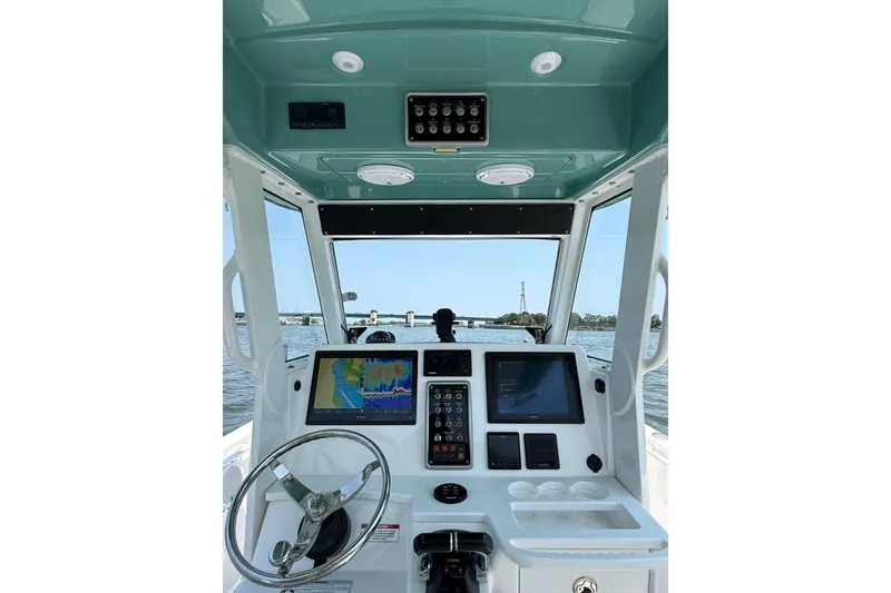 Slide: The Image of 2015 Everglades 295 Center Console boat dashboard with navigation screens and steering wheel. - 21