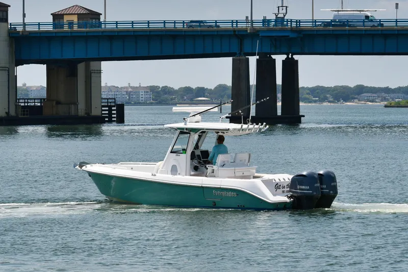 Slide: The Image of 2015 Everglades 295 Center Console boat cruising under a blue bridge. - 7