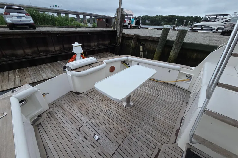 Slide: The Image of 2002 Ocean 56 Super Sport yacht deck with table and seating at dock. - 27