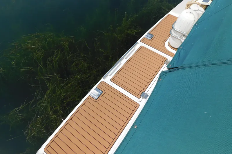 Slide: The Image of 1993 Silverton 34 Express boat deck with teak flooring and green cover. - 7