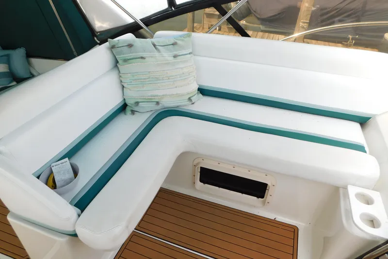 Slide: The Image of 1993 Silverton 34 Express boat interior with white and teal seating, wooden flooring, and a decorative pillow. - 14