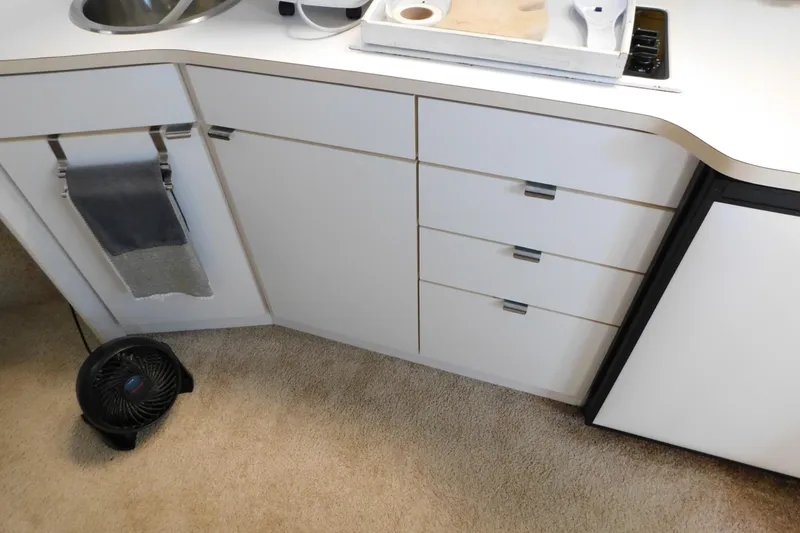 Slide: The Image of Interior of 1993 Silverton 34 Express boat with white cabinetry and compact kitchen setup. - 45