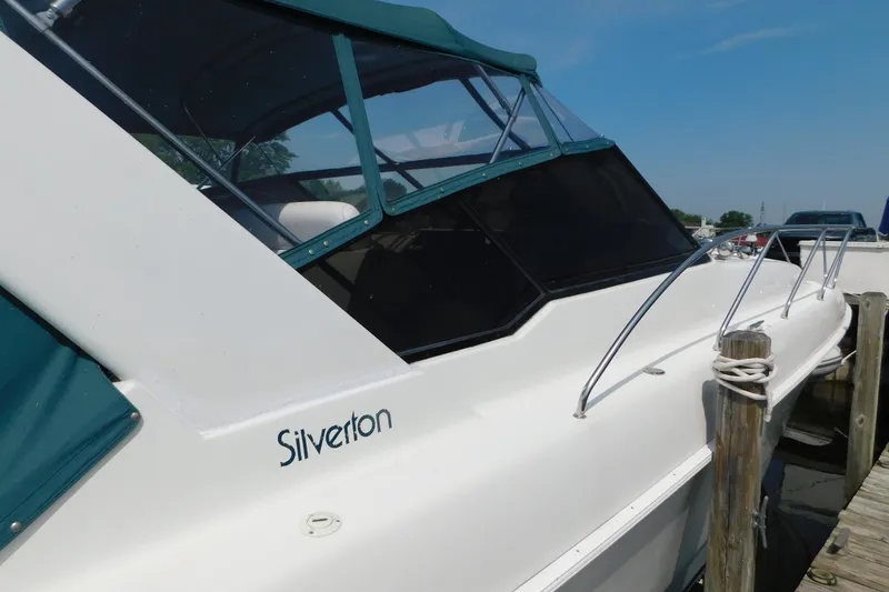Slide: The Image of 1993 Silverton 34 Express boat docked, featuring sleek design and green canopy. - 6