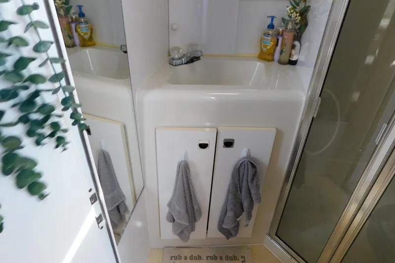 Slide: The Image of Bathroom sink area in a 1993 Silverton 34 Express boat, featuring towels and toiletries. - 66
