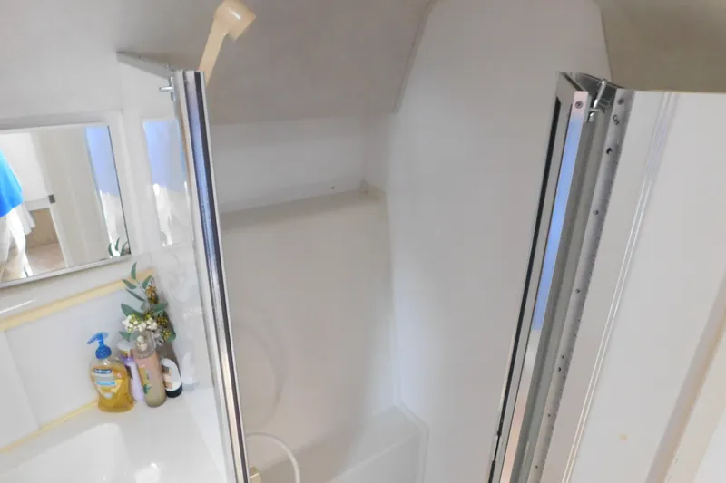 Slide: The Image of 1993 Silverton 34 Express boat bathroom with shower, mirror, and toiletries. - 69