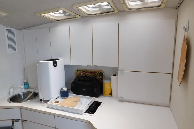 Slide: The Image of Compact kitchen area in a 1993 Silverton 34 Express boat with white cabinets and appliances. - 32