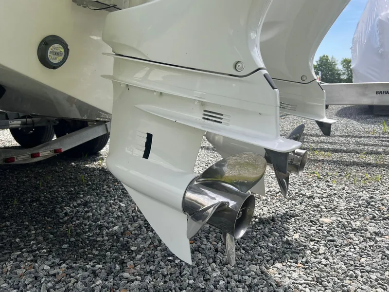 Slide: The Image of Two outboard engines with shiny propellers on a gravel surface, part of an Edgewater 262CC boat. - 5