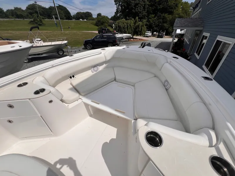Slide: The Image of The image shows the cockpit of a 2021 Edgewater 262CC boat with white upholstery and cup holders. - 34