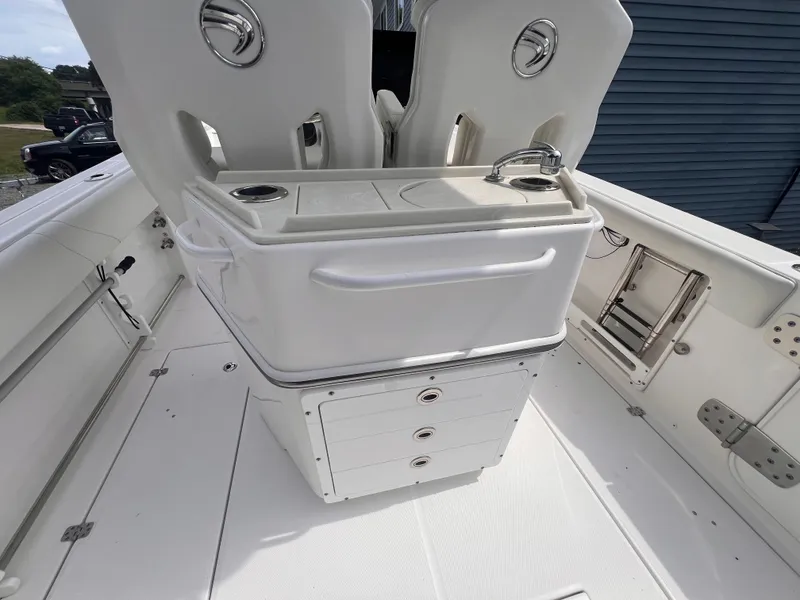 Slide: The Image of The image shows the cockpit of a 2021 Edgewater 262CC boat with a white helm station and storage. - 12