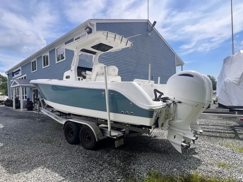 Slide: The Image of A 2021 Edgewater 262CC boat on a trailer in front of a blue building. - 2