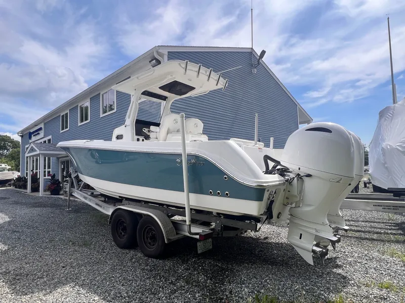 Slide: The Image of A 2021 Edgewater 262CC boat on a trailer in front of a blue building. - 3