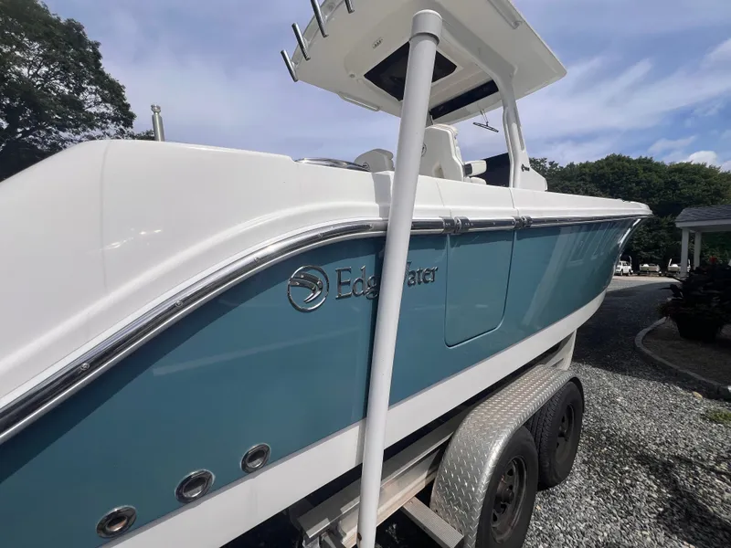 Slide: The Image of A 2021 Edgewater 262CC boat on a trailer. It features a blue and white color scheme. - 8