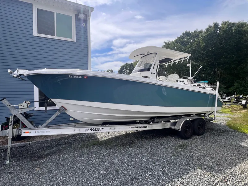 Slide: The Image of A 2021 Edgewater 262CC boat on a trailer next to a blue building. - 1