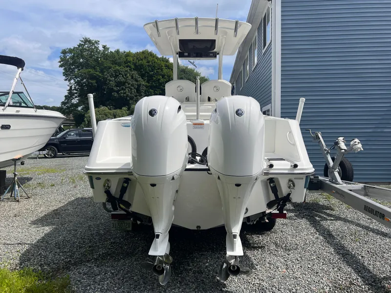 Slide: The Image of A 2021 Edgewater 262CC boat with twin outboard engines is parked on gravel beside a blue building. - 4