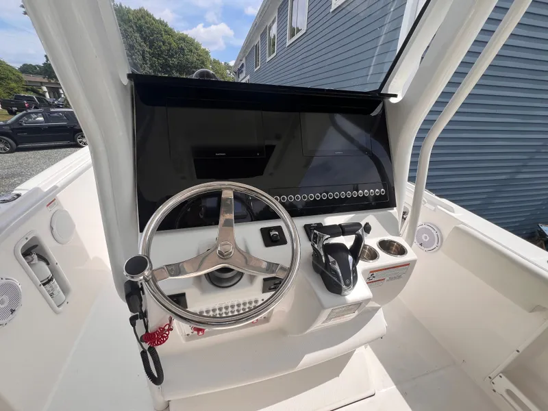 Slide: The Image of The image shows the helm of a 2021 Edgewater 262CC boat. It features a modern steering wheel, throttle, and cup holders. - 21